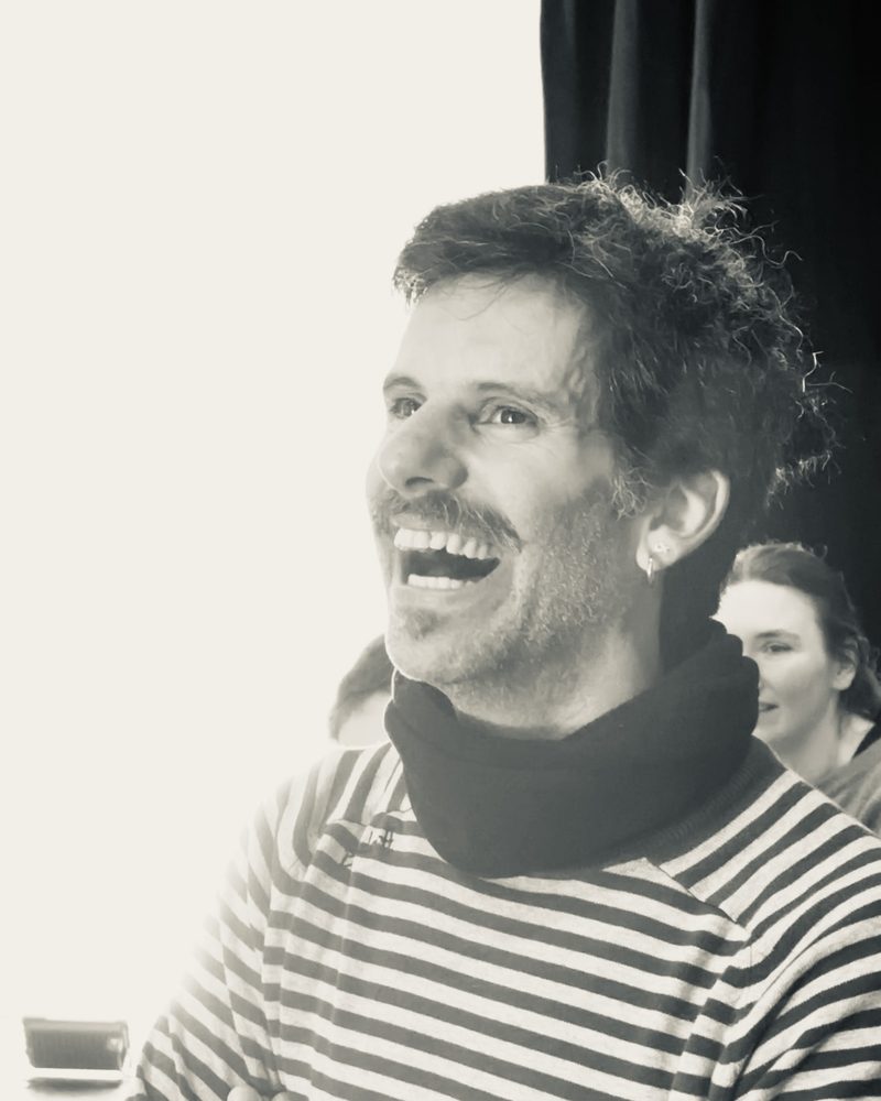 A participant laughing with his head thrown back, lit from the window