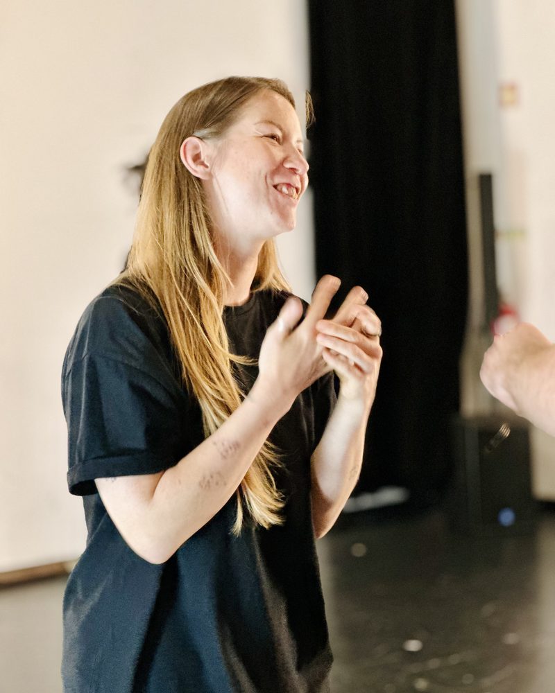 A participant clapping, smiling to herself