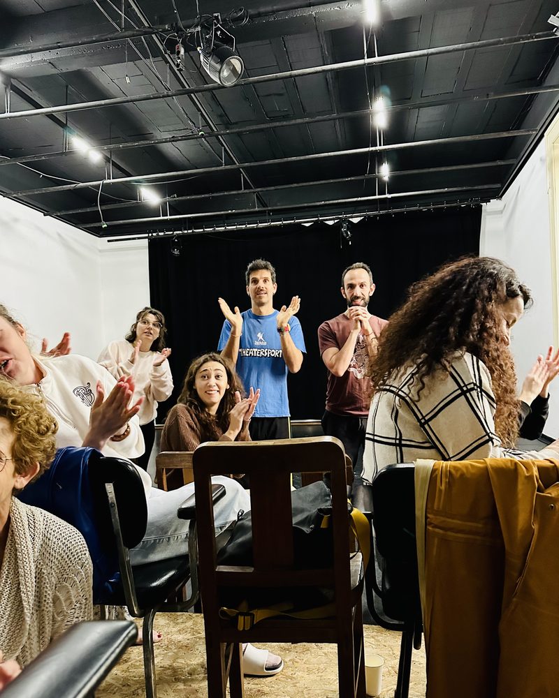 The whole group applauding in the studio, chairs pushed to the side