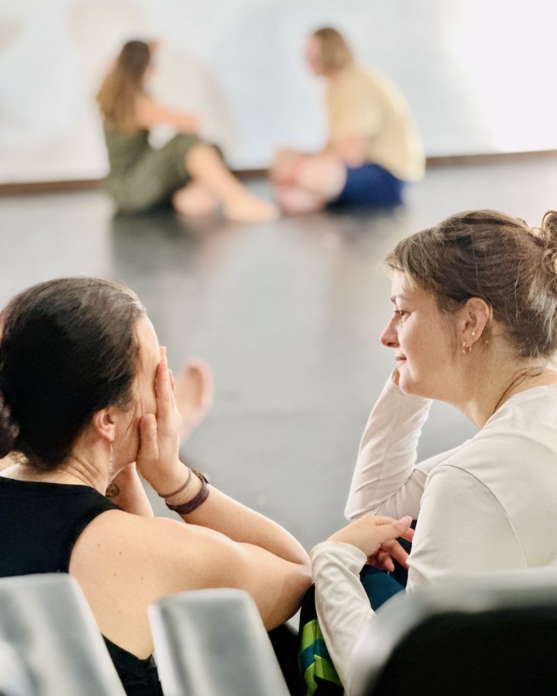 Two participants sitting close, one holding her face in her hands