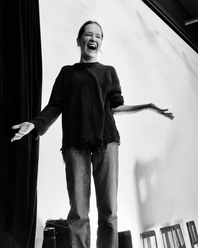 A participant alone in front of the group with her arms wide open