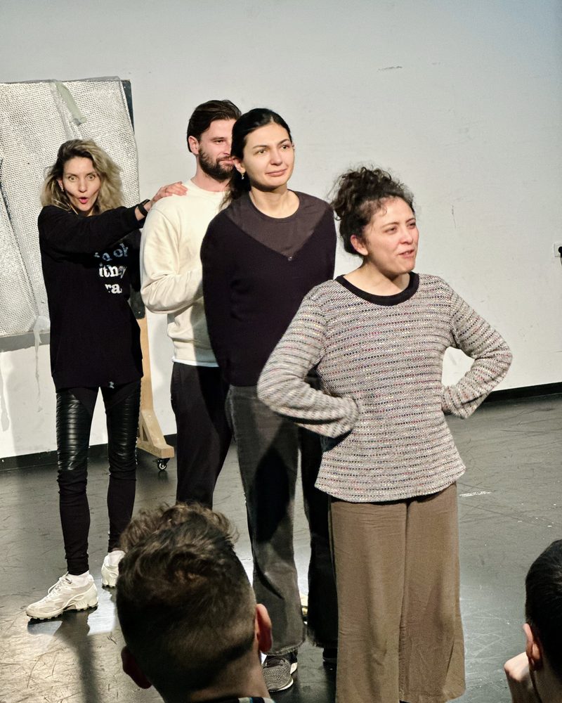 A small group standing together, one participant crouched at their feet