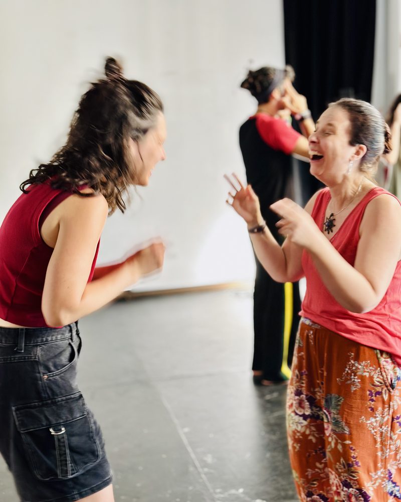 Two participants facing each other, one mid-sound with her hands up
