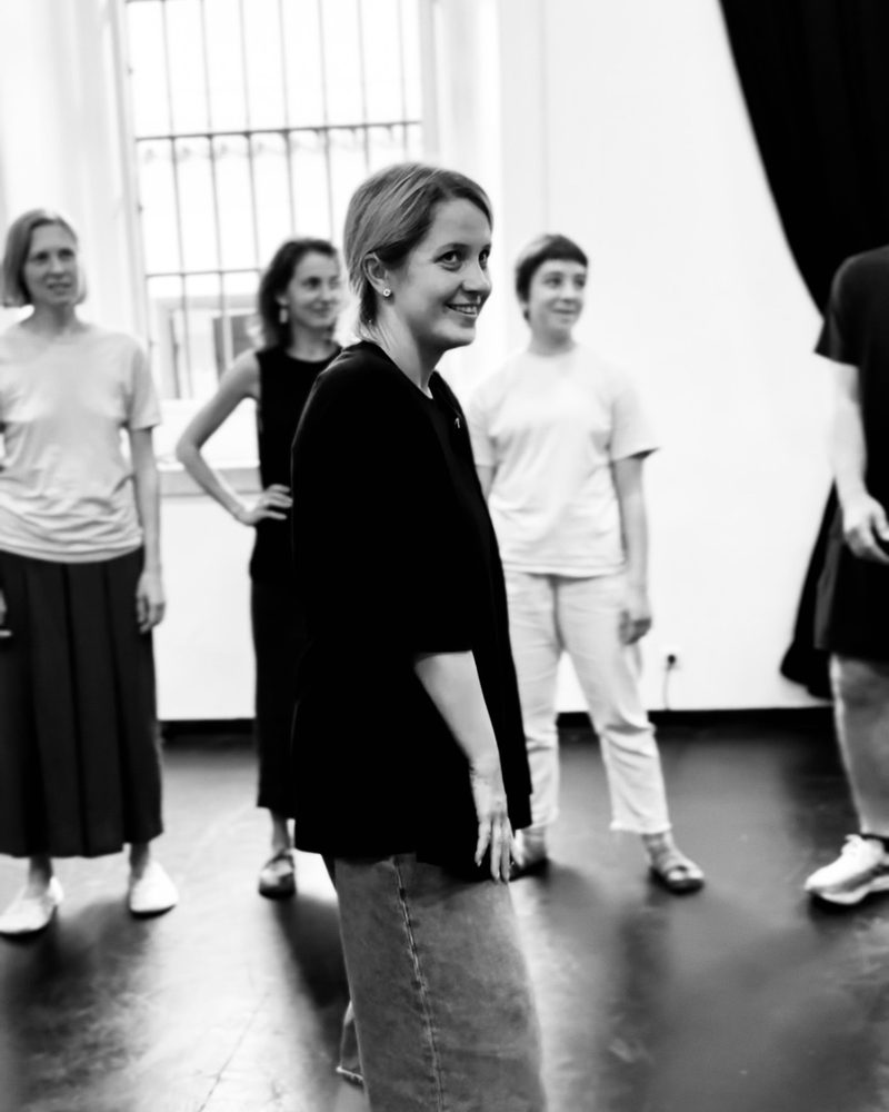 A participant standing alone in front of the group, hands behind her back