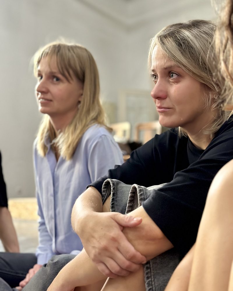 Two participants sitting side by side, one of them moved to tears
